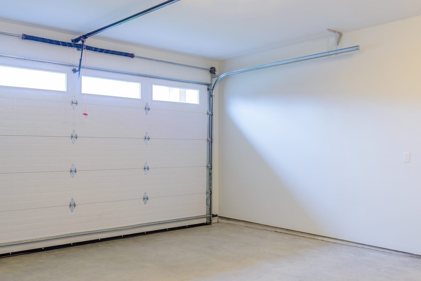 Empty garage interior with closed white door and windows